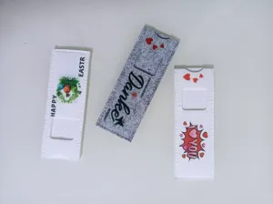 Detail von drei Filzhüllen für Schokoriegel mit festlichen Aufdrucken auf weißem Grund.