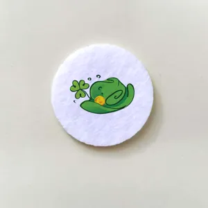 Close-up detail of a white circular badge with a green cartoon shamrock hat design