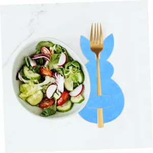 Blue Easter bunny cutlery holder with gold fork on a marble table beside salad.