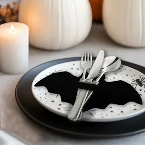 Halloween bat-shaped felt cutlery holder with stainless steel utensils on a plate