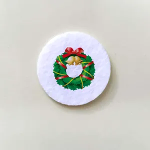 Detail of round white felt Christmas brooch featuring a festive green wreath design