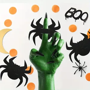 Close-up of green hand with black spider decorations for Halloween party