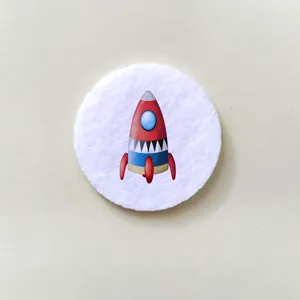 Detailed macro view of a cartoon rocket illustration on a circular white pin badge
