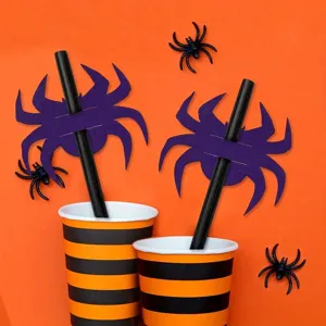 Halloween purple spider straw decorations with striped paper cups on orange background.