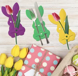 Easter bunny cutlery holders set on festive table with colorful tulips and eggs.