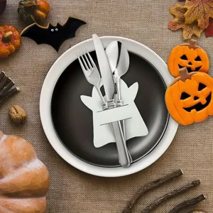 Detail of white ghost cutlery holder on a black plate with Halloween decorations