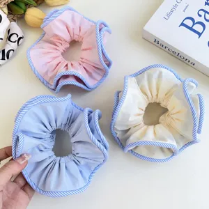 Close-up of pastel fabric scrunchies with blue striped edges in pink and cream.