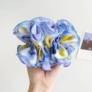 Detailed macro view of a large oil painting style scrunchie with vibrant blue and yellow hues