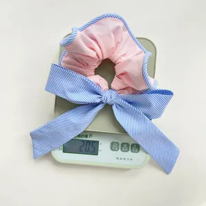 Vista detallada de un coletero con lazo de rayas rosa y azul en una báscula que pesa 20,5 g