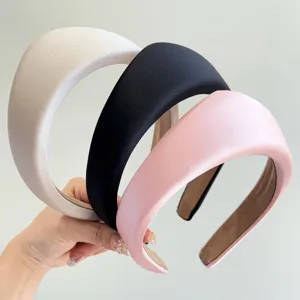 Primer plano de tres diademas acolchadas retro en satén elegante beige, negro y rosa
