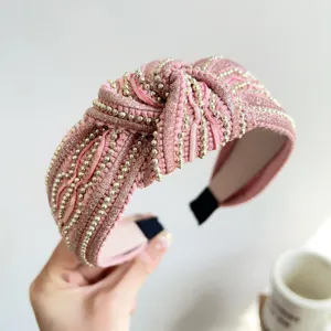 Dettaglio di fascia per capelli rosa annodata con paillettes scintillanti e perline dorate
