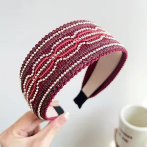Dettaglio di un'elegante fascia larga bordeaux con perle dorate e paillettes scintillanti.