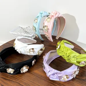 Assorted knotted satin headbands featuring elegant metal flower and pearl decorations