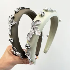 Détail en gros plan de serre-têtes en satin à couronne haute avec accents métalliques chic.
