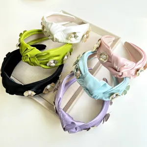 Detailed view of satin knotted headbands with metallic 3D flowers and pearls.
