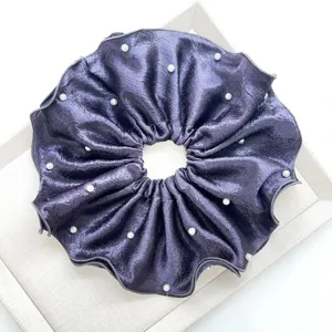 Vista detallada de un coletero de satén plisado violeta oscuro con detalles de perlas