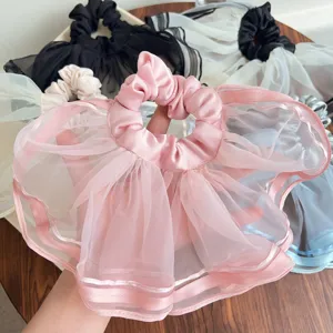 Detailaufnahme der feinen plissierten Netzstruktur eines rosa Organza-Haargummis.