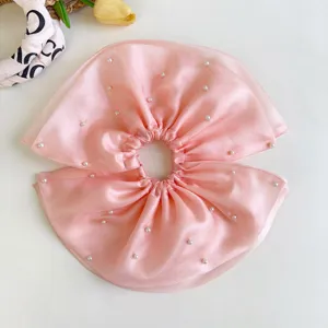 Detalle de un coletero de malla rosa grande con elegantes perlas blancas aplicadas