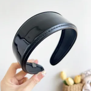 Detailed view of a retro glossy black PU leather wide headband with fine stitching