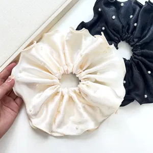 Primer plano de coleteros grandes de satén plisado con elegantes adornos de perlas.