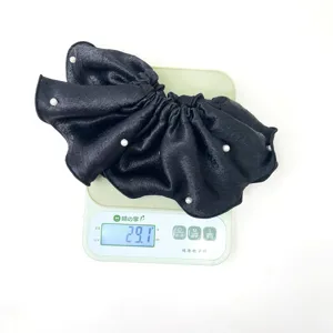Peso de un coletero grande de satén negro con perlas blancas en una báscula digital