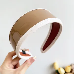 Close-up detail of a vintage Maillard brown PU leather wide headband with white stitched edges
