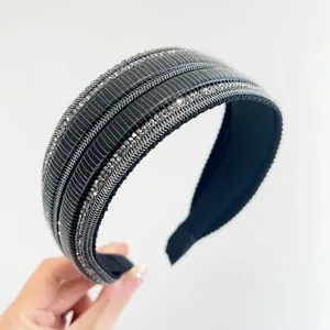 Primo piano di un'ampia fascia nera decorata con file di strass argentati brillanti.