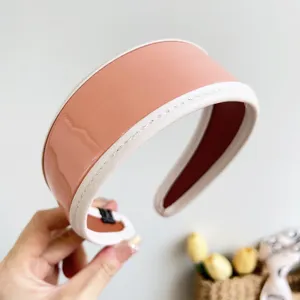 Close-up detail of glossy retro PU leather wide headband with white stitched edges.