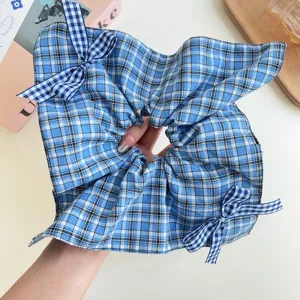 Primo piano dettagliato di uno scrunchie a scacchi blu con fiocchi a quadretti