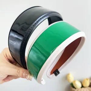 Macro view of wide PU leather headbands in glossy black and green with white trim details