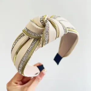 Primo piano del cerchietto con nodo, strass e dettagli dorati su ecopelle beige di lusso