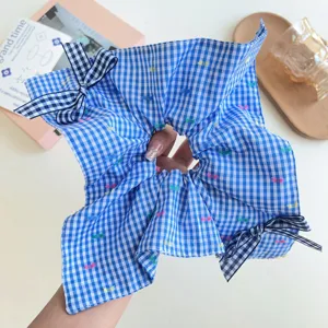 Vista dettagliata di uno scrunchie oversize a quadretti blu con graziosi fiocchi.