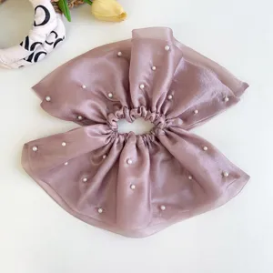 Detalle de cerca de un coletero de malla color malva con delicadas perlas blancas