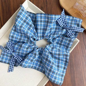 Dettaglio di un elastico per capelli a scacchi blu con graziosi fiocchi in stile college.