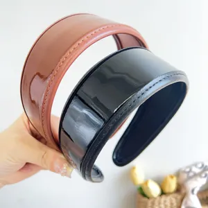 Close-up detail of glossy PU leather wide padded headbands in brown and black finishes.