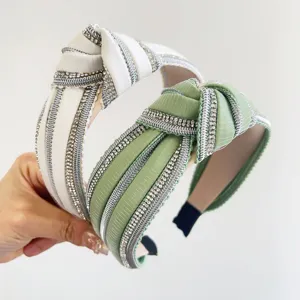 Vista dettagliata di due eleganti cerchietti annodati decorati con strass in bianco e verde.