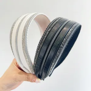 Primo piano di eleganti cerchietti bianchi e neri con dettagli in strass lucidi.