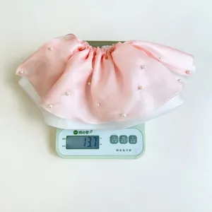 Vista de detalle que muestra el peso de 13,7g de un coletero rosa de perlas en una báscula