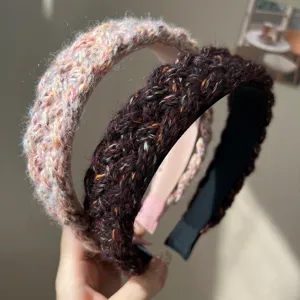 Close-up of two chunky braided wool headbands showing detailed knit texture and colors.