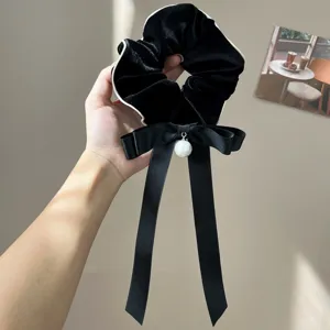 Close-up of black velvet scrunchie with large satin bow and pearl charm