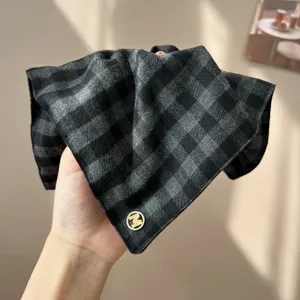 Close-up of a vintage gray plaid sponge headband with a gold metal 'M' logo detail