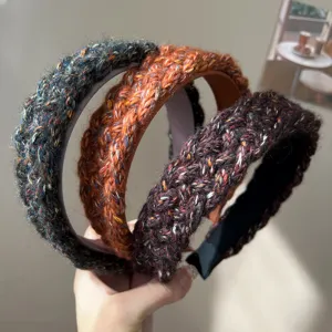 Close-up of three colorful knitted braided wide headbands with textured yarn finish.