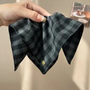 Close-up of grey and black checkered padded headband with small gold logo detail