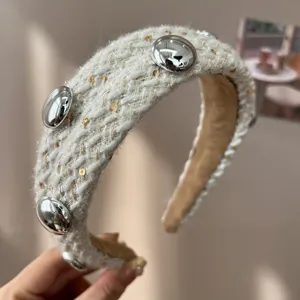 Detail of cream tweed padded headband featuring silver dome buttons and subtle gold sequins