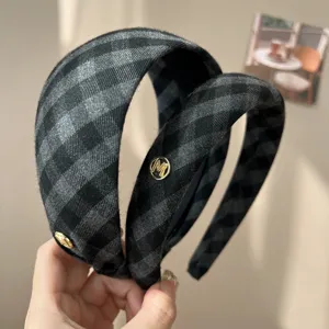 Detailed view of a stylish retro gray plaid sponge headband featuring a gold 'M' emblem