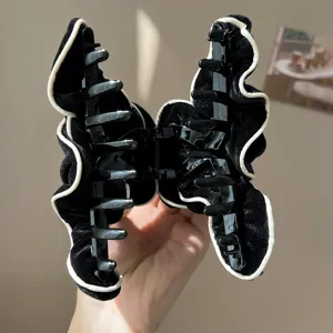 Close-up of a black velvet hair claw clip with elegant white ruffled edges