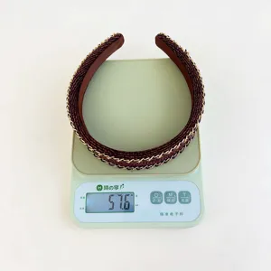 Detailed view of red woven wide headband with gold chains weighing 57.6g on a scale