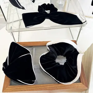 Detailed view of black velvet hair scrunchies and bow clips with white contrast edges