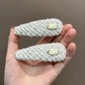 Set of two elegant cream tweed hair clips with decorative golden bow metal plaques