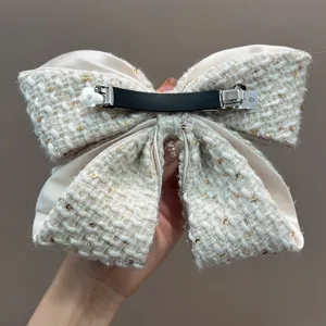 Detailed view of the tweed bow hair clip back showing the sturdy metal fastener.